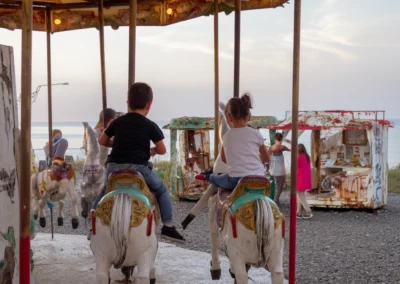 Children seen from behind riding an old merry-go-round