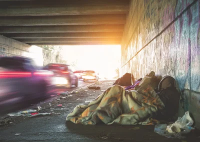 A homeless person sleeping under a bridge